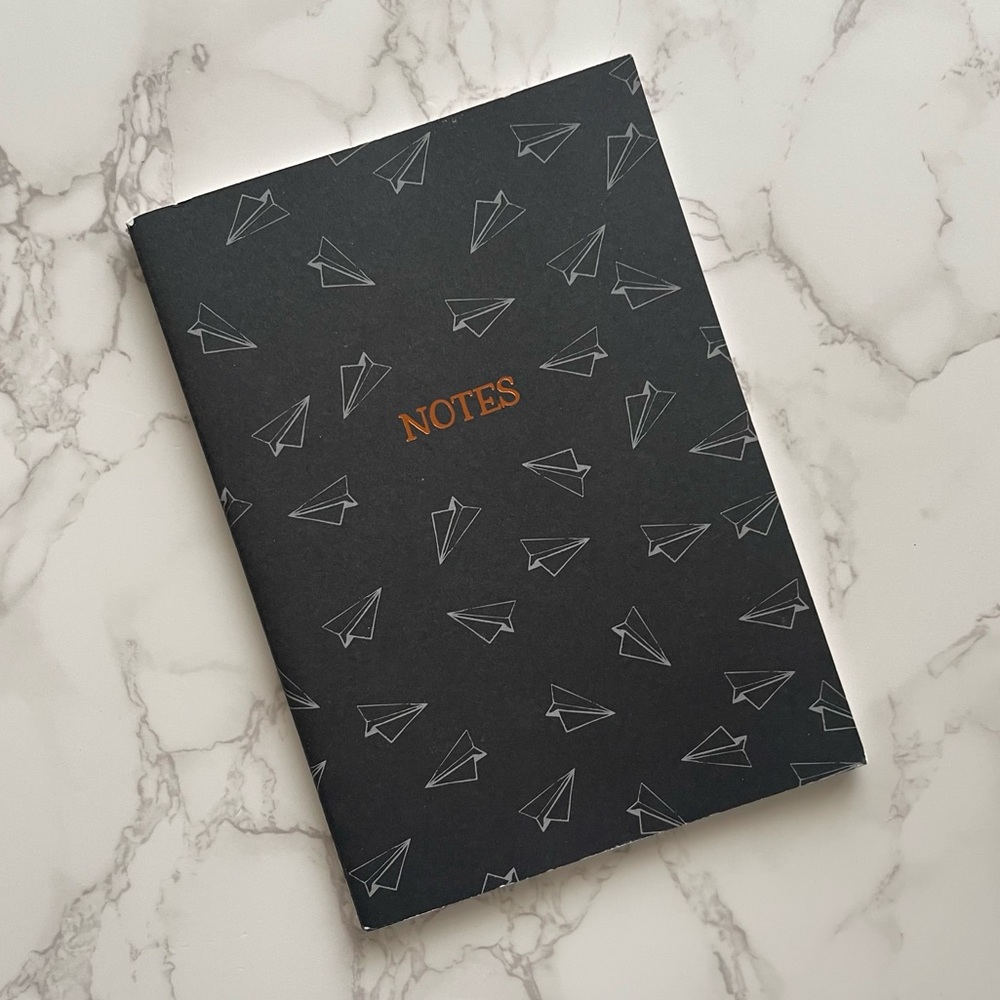Notebook with paper airplane pattern on exterior and rose gold “NOTES” on front